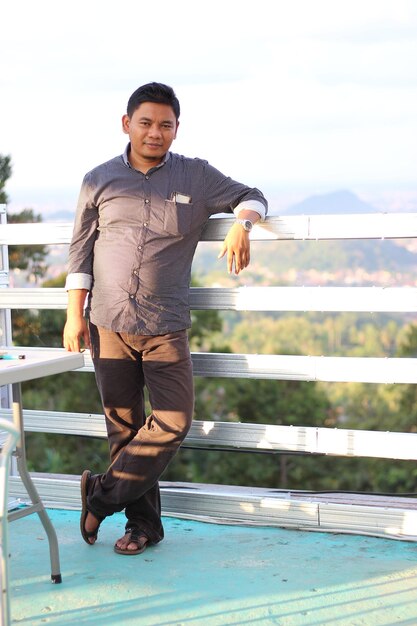 Portrait of man standing against railing