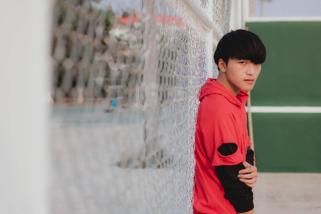 Photo portrait of man standing by chainlink fence