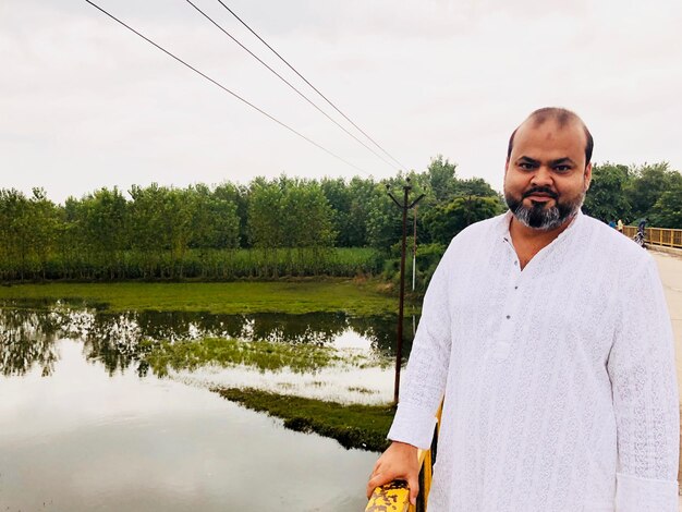 Portrait of man standing by lake against sky