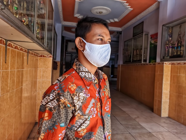 Portrait of a man standing at home in a mask