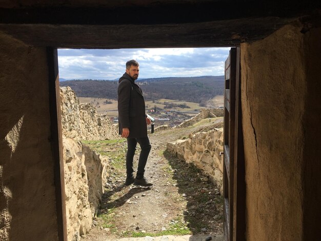 Foto ritratto di un uomo in piedi sulla montagna visto attraverso l'ingresso contro il cielo