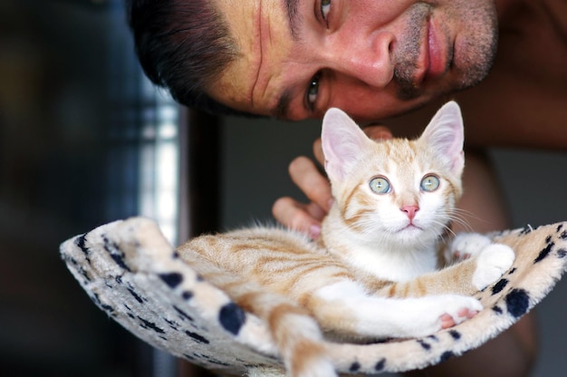 スクラッチポストに座っている猫を撫でている男の肖像画