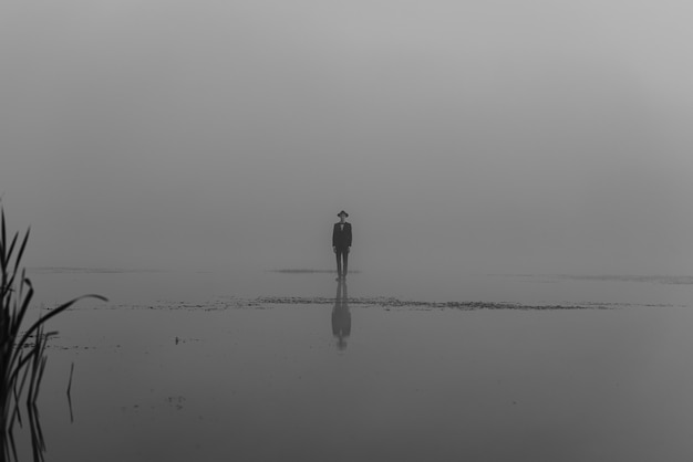 Portrait of a man in a suit with a hat standing on the water