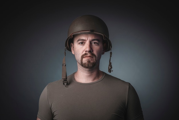 Portrait of a man in a t-shirt wearing a soldier military helmet,