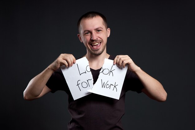 Portrait of a man tearing up an inscription on paper looking for a job