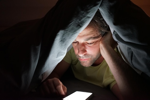 Portrait of man using mobile phone on bed