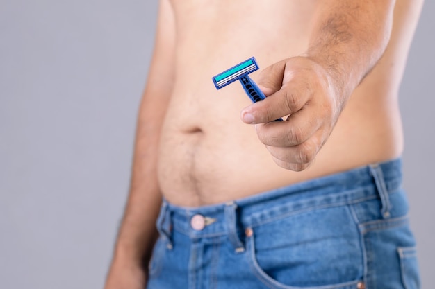 Portrait man using razor blade to cutting belly and body hair.