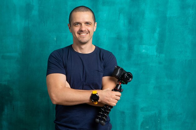 Portrait of man videographer or blogger with camera on tripod in hands looking in camera