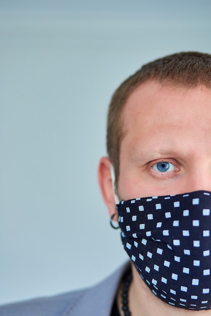 Portrait of man wearing black mask at grey background.