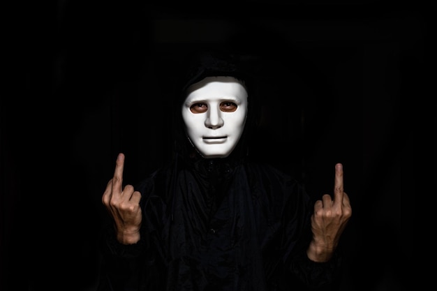 Photo portrait of man wearing mask gesturing against black background