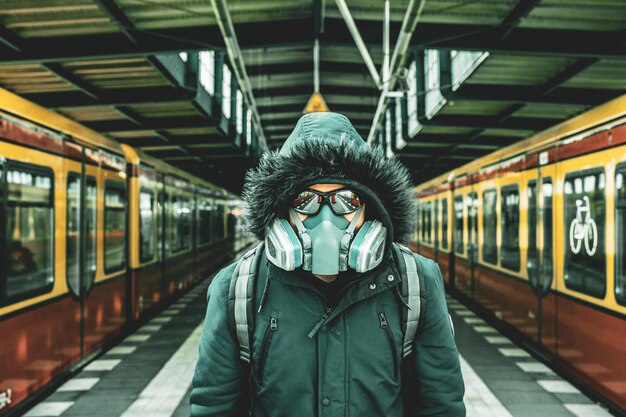 Foto ritratto di un uomo che indossa una maschera in piedi sulla piattaforma della stazione ferroviaria