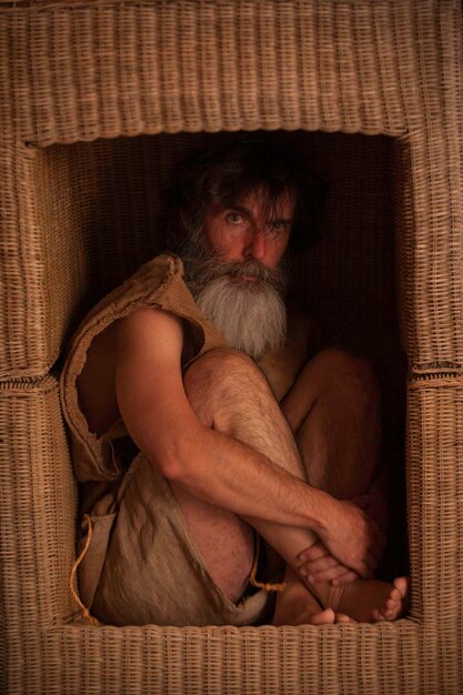 Photo portrait of man wearing sack sitting in box shape