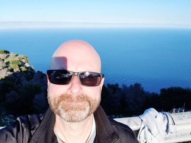 Foto ritratto di un uomo che indossa occhiali da sole contro il mare