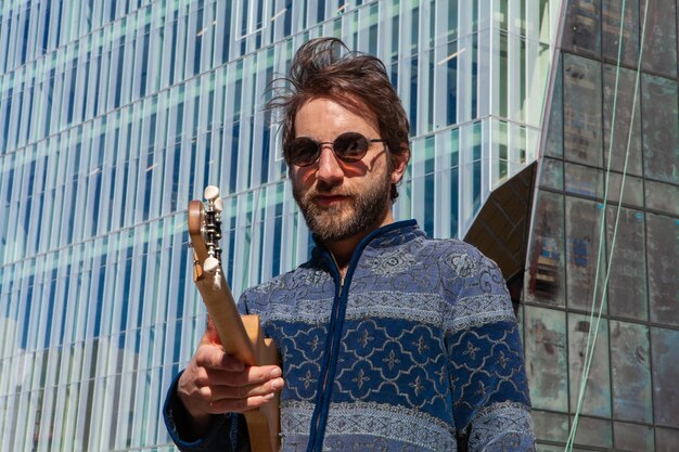 Photo portrait of man wearing sunglasses holding guitar while standing outdoors