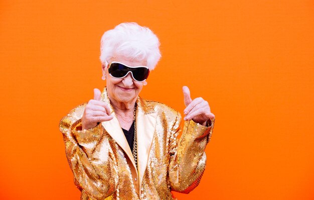 Portrait of man wearing sunglasses standing against orange background