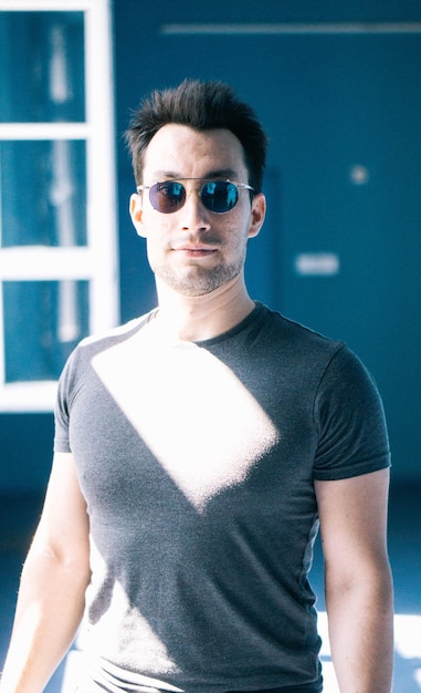 Photo portrait of man wearing sunglasses while standing against wall