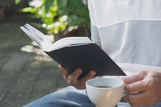 Портрет мужчины носить футболку. Man оставаться в парке для чтения книги и пить кофе.