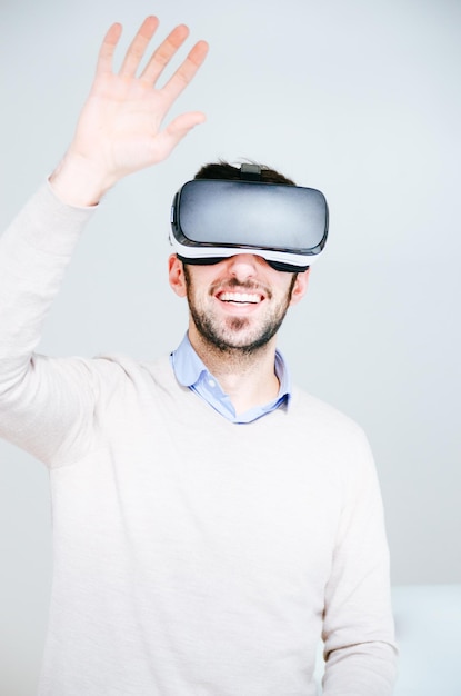 Portrait of man wearing virtual reality simulator against white background