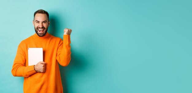 Portrait of man with arms raised standing against blue background