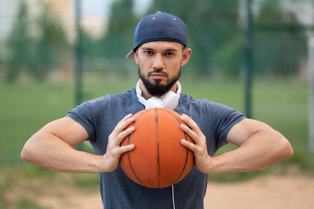 Ritratto di un uomo con un pallone da basket in mano per strada