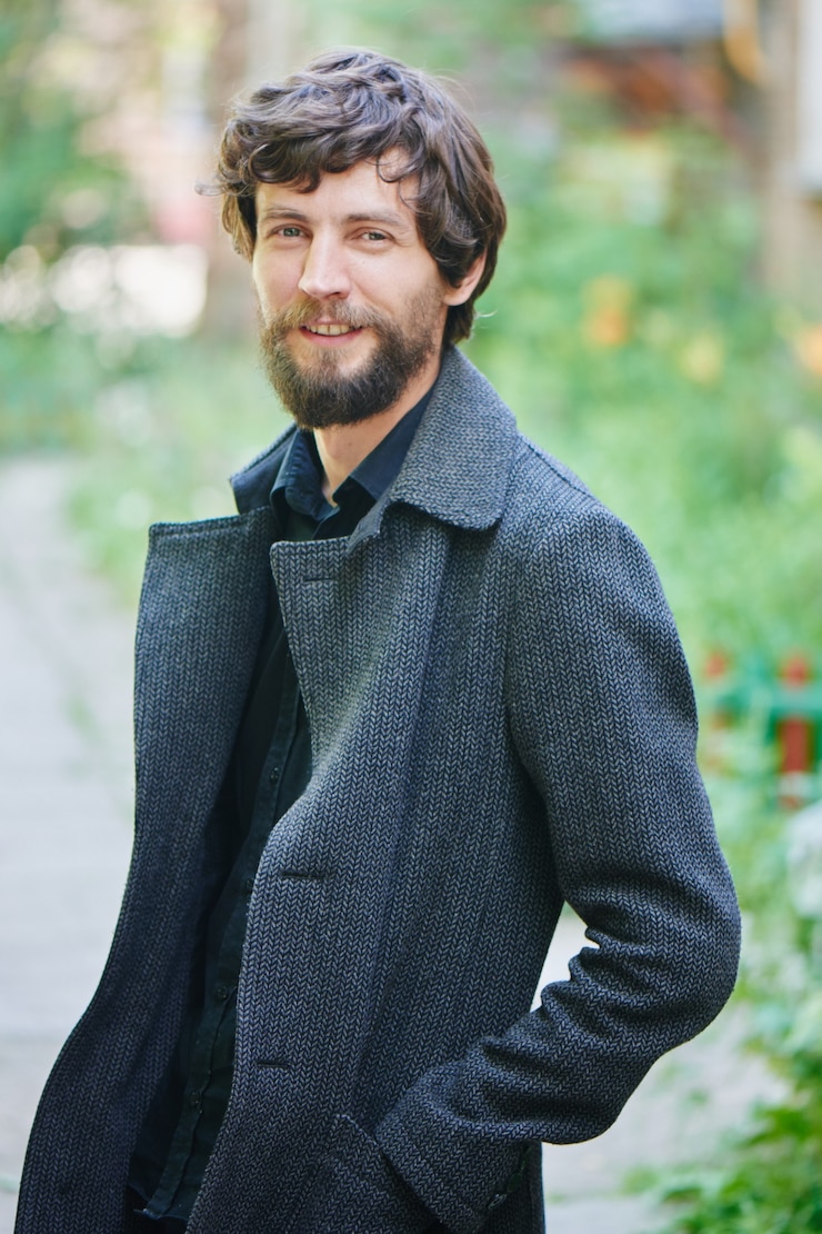 Photo portrait of a man with a beard in a dark coat in the city