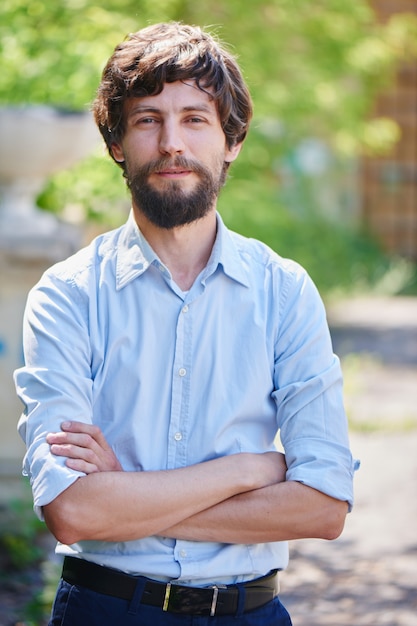 Photo portrait of a man with a beard in a shirt in the park