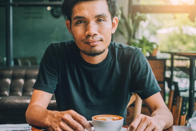 カフェに座っているコーヒーを持った男の肖像画