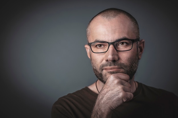 Portrait of man with glasses and hand on chin. 