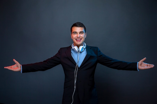 Portrait of man with headphones on dark wall with smoke.