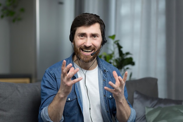 Photo portrait of a man with a headset working online consultant at home focused and angry talking to a client looking at the webcam