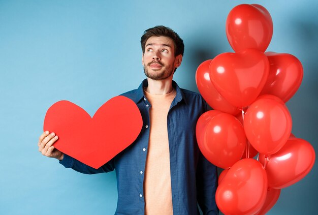 Portrait of man with heart shape standing against blue background