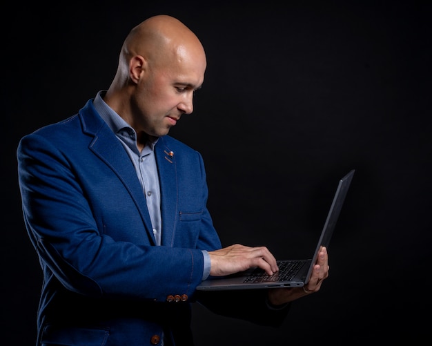 Portrait of man with laptop in studio on black background