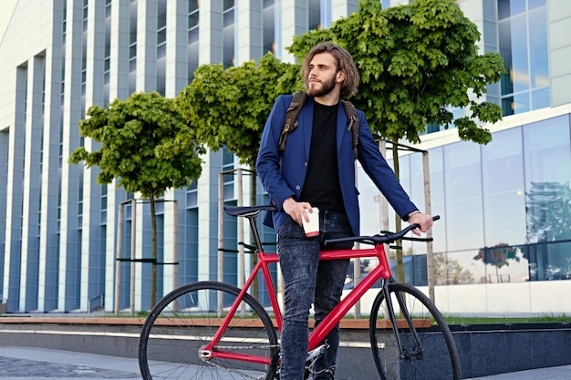 Portrait of a man with long blond hair with single speed bicycle in a city park.