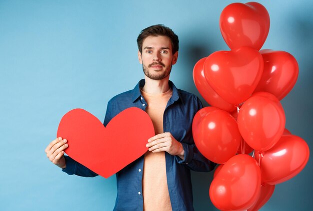 Portrait of man with red balloon against blue background