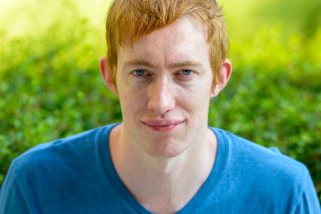 Portrait of man with red hair relaxing in the park outdoors