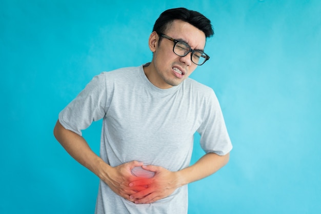 Portrait of man with stomachache isolated on blue background