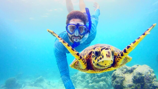 Foto ritratto di un uomo con una tartaruga che nuota in mare