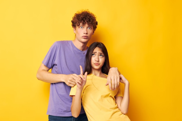 Portrait of a man and a woman casual clothes posing emotions antics yellow background unaltered