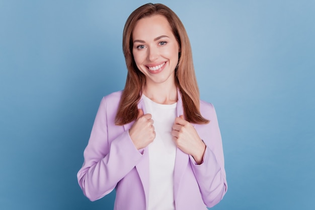 Portrait of manager woman touch blazer isolated on blue background