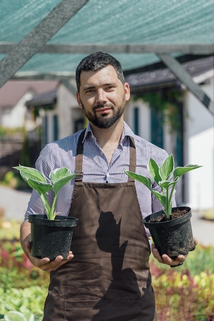 Портрет садовника с многолетними растениями в руках в садовом центре