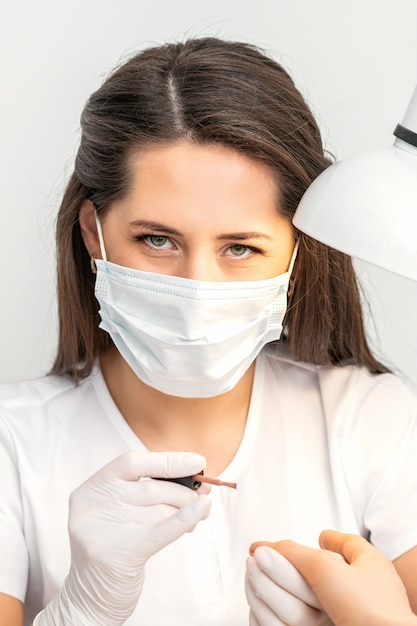 Portrait of manicure master with white protective mask working in beauty salon