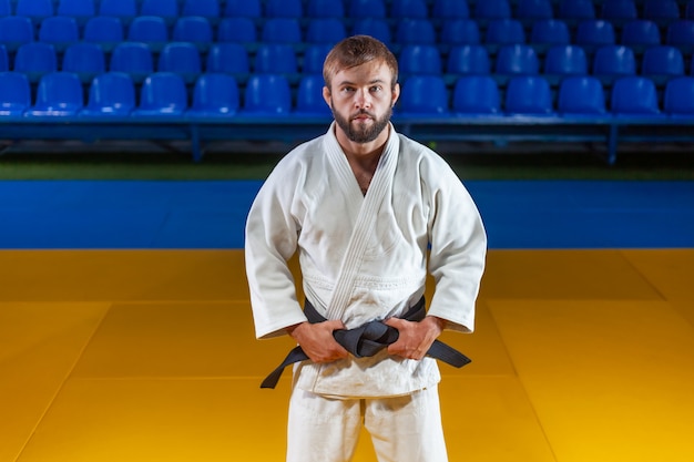 Photo portrait of martial artist in white kimono with black belt indoor