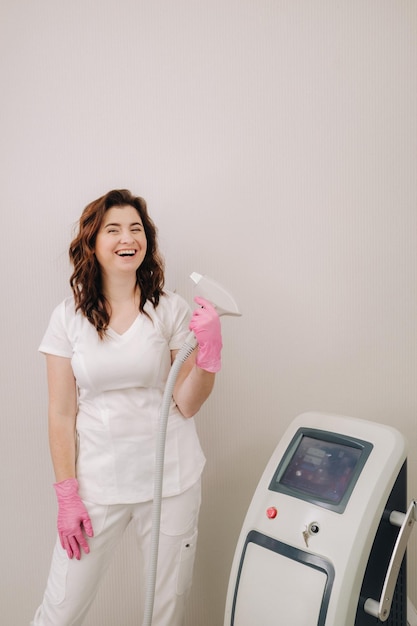 Portrait of the master of laser hair removal a woman in a white\
coat holds a laser hair removal devi