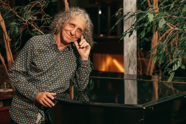 65세 남성 음악가가 손에 그랜드 피아노를 기대고 있는 초상화