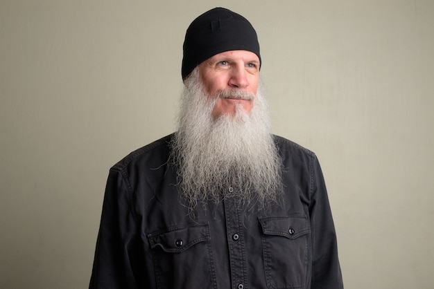 Portrait of mature bald man with long gray beard against white wall