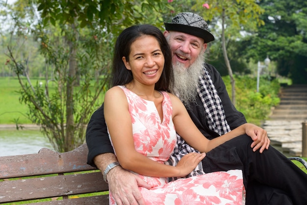 Portrait of mature bearded man and mature Asian woman as married couple