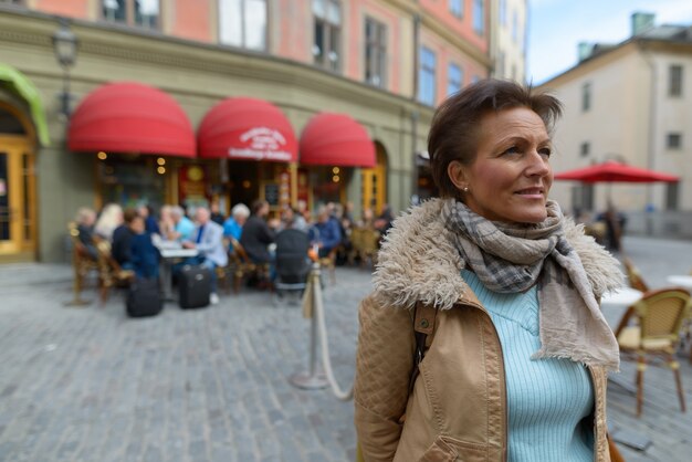 Portrait of mature beautiful Scandinavian tourist woman with short hair traveling around the city of Stockholm in Sweden