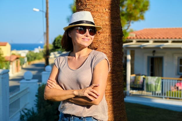 Ritratto di bella donna sorridente matura in vacanza, paesaggio tropicale estivo, mare all'orizzonte, spazio copia. riposo, bellezza, felicità, donne di mezza età