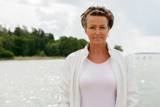 Portrait of mature beautiful woman against scenic view of the lake and sky in nature