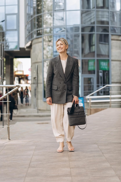 Portrait of a mature business woman smiling with emotions on a modern office and urban background